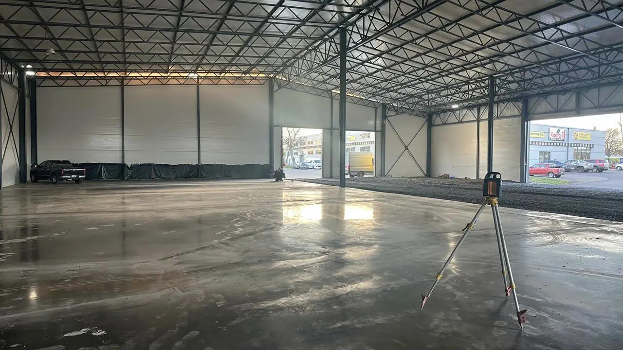The finished, trowel-polished warehouse floor with a mirror-like sheen reflecting light from the gate